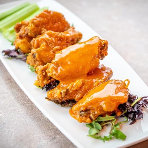 Happy Days Finer Diner's buffalo wings, coated in orange sauce, served with celery sticks.