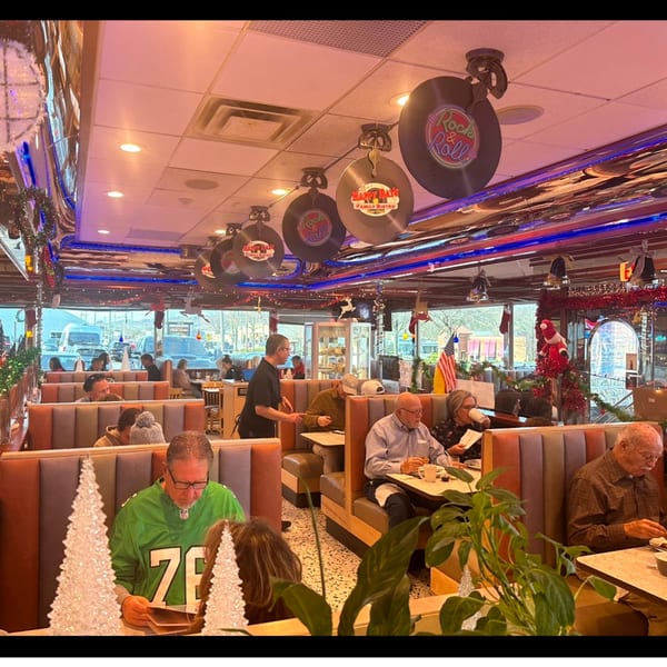 Happy Days Finer Diner interior with patrons in booths, a server, and festive holiday decorations.