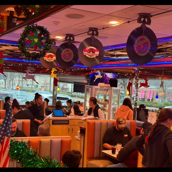 A bustling Happy Days Finer Diner interior, decorated for Christmas, with customers seated in booths.